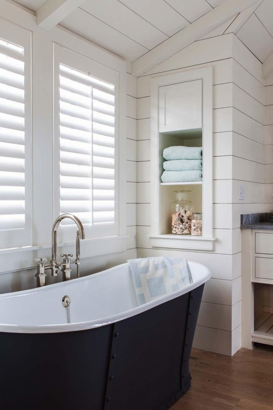 White plantation shutters on bathroom window next to bathtub