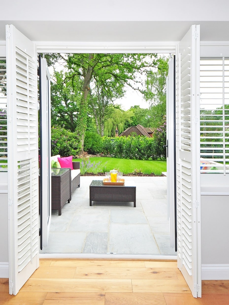 Plantation shutters with view of patio and trees outside